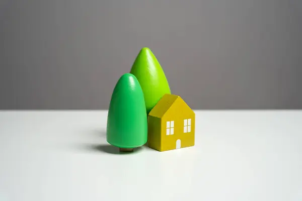 House with trees, figurine. Environmental friendliness and autonomy of housing. High energy saving technologies, in harmony with nature. Buying a nice house. Garden work, landscape design.
