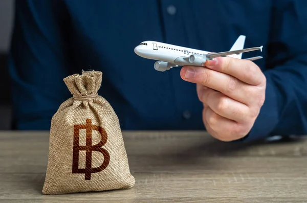 Airplane flights and thai baht money bag. Airline industry income. Budget allocations. Investments in the development of the air transport industry and infrastructure.