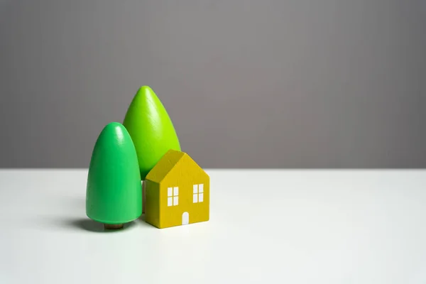House with trees. Buying a nice house. Garden work, landscape design. Figurine