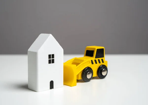 Bulldozer demolishing the house - concept. Illegal buildings construction. Lawsuit. Illegal construction or demolition of a building. Plan for the renewal and restoration of residential areas.