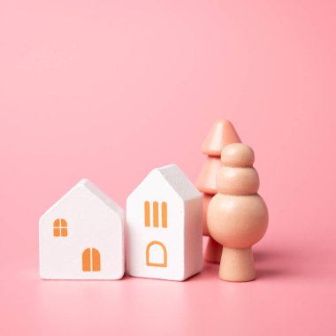 Pastel pembe renkli ev ve ağaçlar. Emlakçı servisi. Satın alma ve satma. Konut seçenekleri. Uygun fiyatlı konutlar. İpotek.