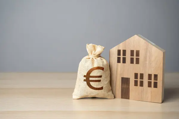 Wooden house and euro money bag. Taxes. Buying and selling real estate. Housing prices. Property value appraisal. Make a deal. Property Insurance.