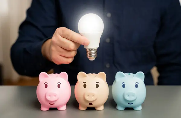 Businessman holding a light bulb over a piggy bank. Choose the best investment idea. New ways to save money. Invest. Open a deposit. Invest in business. Ingenuity and creativity. Eureka moment