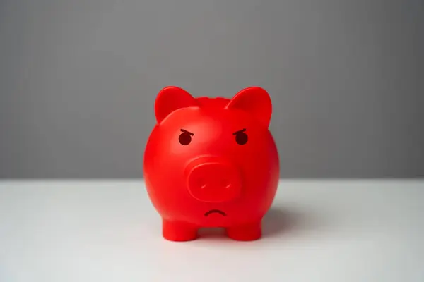 Angry red inflated piggy bank. Overheated financial market. Difficult economic conditions. Threat to savings. Heavy burden on the budget, high expenses and the likelihood of bankruptcy.