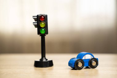A toy blue car near a traffic light on the table. Traffic and driving rules concept clipart