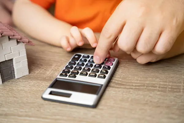 Father and child count on a calculator. Concept of budget planning and payment of utility bills. Saving money to buy or rent a new house, apartment or home. Finance savings concept