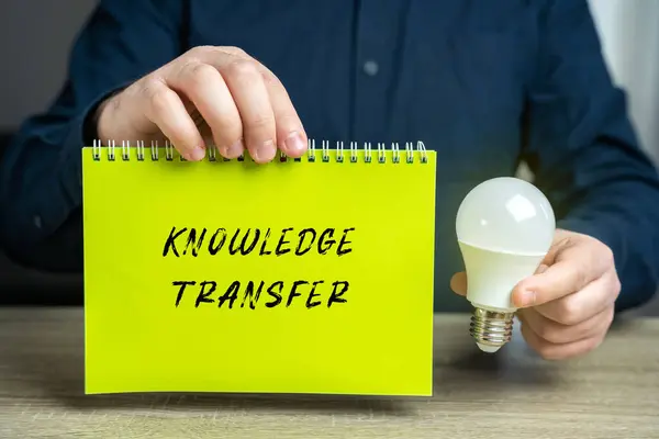 Knowledge transfer concept. Transferring knowledge from one part of the organization to another and the providing of inputs to problem solving. Businessman holding a notepad and idea light bulb