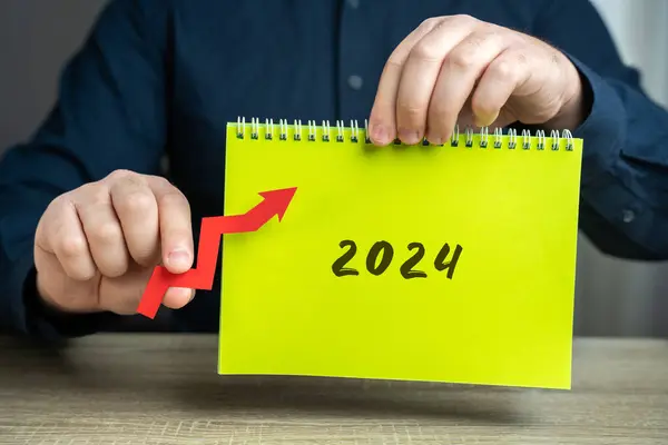 Notebook 2024 and up arrow. The forecast concept for new year. Business forecasting and performance. Growth and development of business and economy. Investments, profit. Businessman