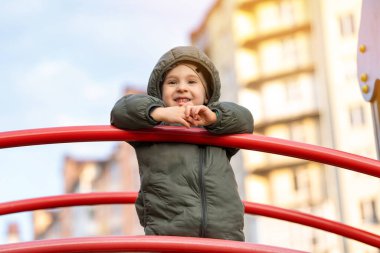 Çocuk parkında uzaktan bakarak gülümseyen üç yaşında bir çocuk. Çocukluk ve yaşam tarzı kavramı. Portre fotoğrafı