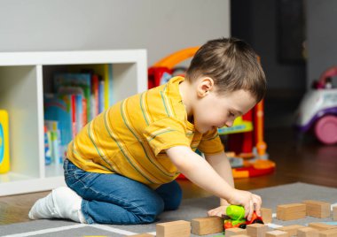 Bandajlı ya da bacağında alçı olan küçük çocuk oyuncaklarla ve bloklarla oynuyor. Çocuklarda ayak ve parmak kırığı. İnsan sağlığı ve tıp konsepti