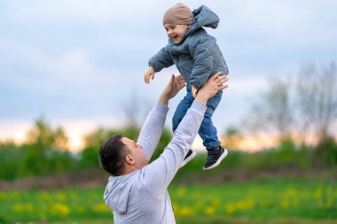 Babam üç yaşındaki mutlu oğlunu bahar günü bir tarlaya fırlatıyor. Aile hayatı ve boş zaman.