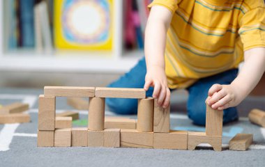 Üç yaşında tahta bloklarla oynayan küçük bir çocuk. Çocuklar için eğitici aktiviteler. Çocuk odası. Kapalı