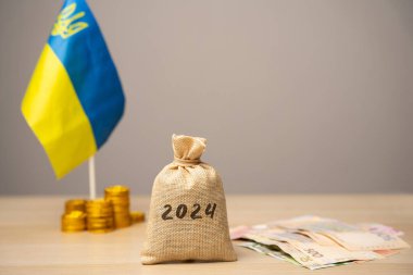 Ukrayna bütçesi ve 2024 finansmanı. Finansal destek ve bağış. Savaştan etkilenen Ukraynalılara yardım etme kavramı. Finansal bağış. Para çantası, Ukrayna bayrağı ve sikkeler, Ukrayna banknotları