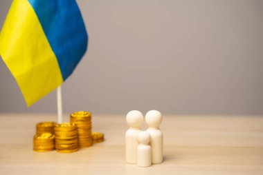 The concept of helping Ukrainian residents affected by the war. Financial support and donation. Economy, finance and fund. Family figures near the Ukrainian flag with coins clipart