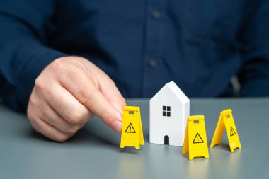 A man installs restriction signs around the house. Asset freezing. Property seizure. Foreclosure for debts and non-payment of mortgages. Emergency housing requiring repair. Building contamination. clipart