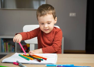 İki yaşında küçük tatlı bir çocuk evdeki çocuk odasında albümde işaretlerle resim çiziyor. Çocuklar için eğitici aktiviteler. Seçici odak.