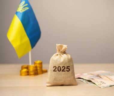 Ukrayna bütçesi ve 2025 finansmanı. Finansal destek ve bağış. Savaştan etkilenen Ukraynalılara yardım etme kavramı. Finansal bağış. Para çantası, Ukrayna bayrağı ve sikkeler, Ukrayna banknotları