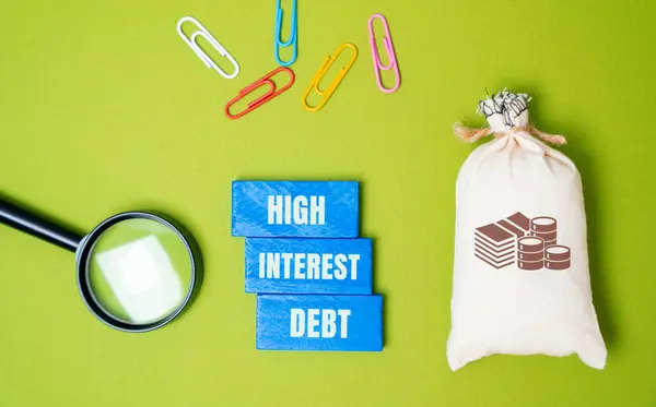 stock image High-interest debt concept - borrowed money with a high interest rate. Wooden blocks with an inscription, a money bag and a magnifying glass. Business and finance