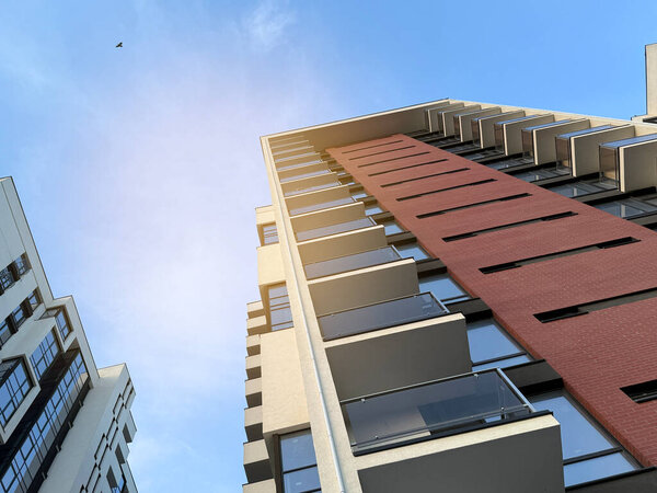 Вид на многоэтажные здания в современном жилом комплексе в солнечный день на фоне голубого неба. Небоскрёбы и недвижимость