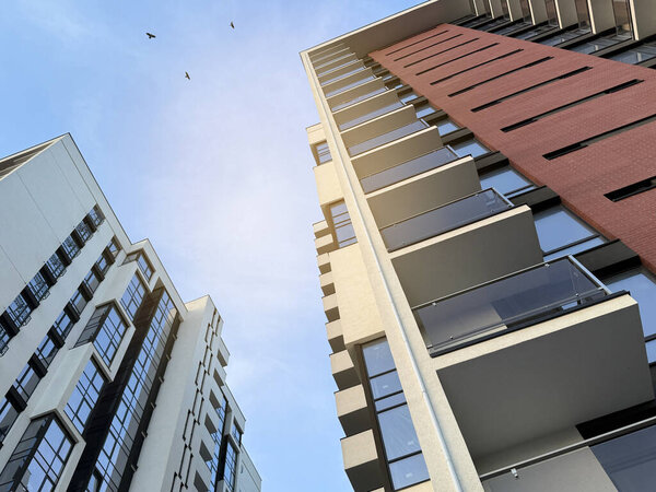 Вид на многоэтажные здания в современном жилом комплексе в солнечный день на фоне голубого неба. Небоскрёбы и недвижимость