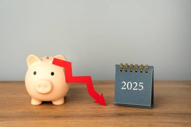 Piggy bank with a downward arrow and a 2025 calendar. Economic crisis and recession. Bankruptcy and financial crisis. Analysis and analytics. Capital outflow. GDP. Forecasting. clipart