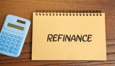 Üzerinde yazı Rafineri ve hesap makinesi olan bir defter. Mevcut krediyi yeni bir krediyle değiştirme süreci, daha iyi şartlar sağlamak için, örneğin daha düşük faiz oranı veya aylık ödemelerin azaltılması gibi