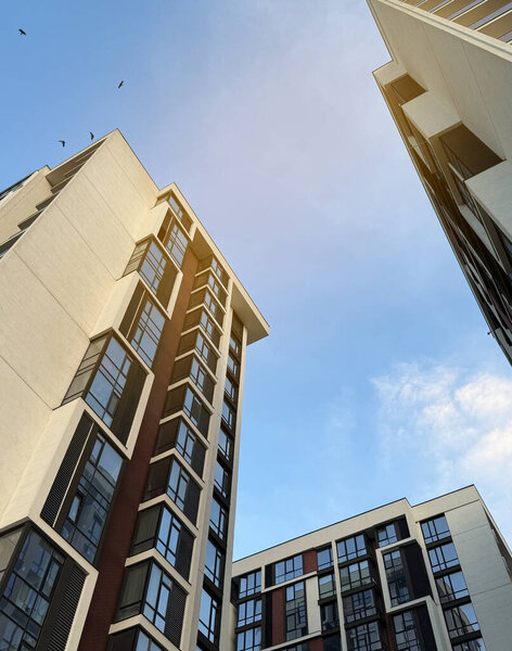 Вид на многоэтажные здания в современном жилом комплексе в солнечный день на фоне голубого неба. Небоскрёбы и недвижимость