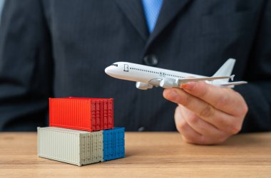 Bir iş adamı kargo konteynırlarının üzerinden havalanan bir kargo uçağı tutuyor. Kargo ve malların hava taşımacılığı kavramı. Paketler, yabancı pazarlardan online siparişler. Hava postası.