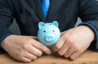 Bir işadamı kumbarayı elinde tutuyor. Tasarruf ve mali politika kavramı. Tasarruf ve sermaye. Krediler ve mevduatlar.