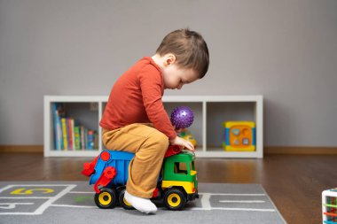 2-3 yaşlarında küçük beyaz bir çocuk oyuncak bir çöp kamyonuna biniyor. Mutlu çocukluk kavramı