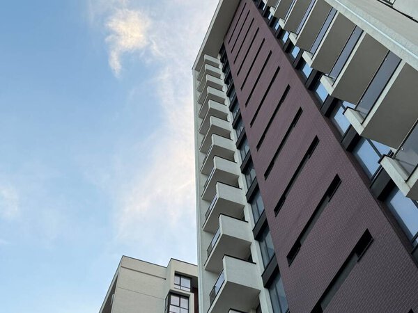 Вид на многоэтажные здания в современном жилом комплексе в солнечный день на фоне голубого неба. Небоскрёбы и недвижимость