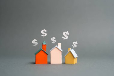 Ev figürleri ve dolar sembolleri. Emlak alıp satmak. Kiralık. Piyasa eğilimleri, konut fiyatları, ipotek oranları ve yatırım fırsatları emlak sektörü ve mali planlamayı etkiliyor