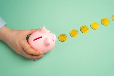 Bir el, kumbarayı altın paralardan oluşan bir patika boyunca idare ediyor. Birikmiş para kavramı. İstikrarlı tasarruf artışı, finansal planlama ve zenginlik inşa etme. Bütçe stratejileri