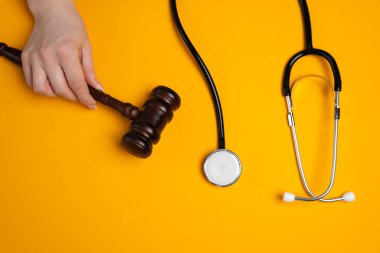 Kadının biri steteskopun yanında yargıç tokmağı tutuyor. Tıp hukuku, sağlık suçları ve dolandırıcılık konsepti. Tıbbi kurallar