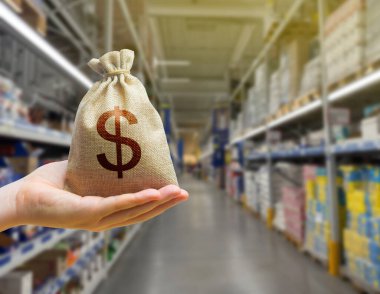 Bakkal tezgahının arka planında ürünlerle dolu para çantası var. Malların maliyeti kavramı. Market seti. İthalat ve ihracat. Toptan satış.