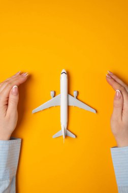 Eller sarı arka plandaki yolcu uçağını korur. Uçak seyahati sigortası, turizm sigortası. Sivil havacılık endüstrisinin korunması. Havayolu düzenleme temaları.