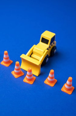 Bir buldozer bir trafik konisi sınırını zorluyor. Sınırları genişletmek ve kuralları gevşetmek. Deregülasyon, politika gevşemesi veya gelişim veya yönetimdeki yasal sınırların genişletilmesi.
