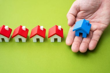 El, mavi evi diğerlerinin sırasına teslim eder. Bir ev al ya da sat. Konut piyasasında mülk alımı, satış veya seçim.