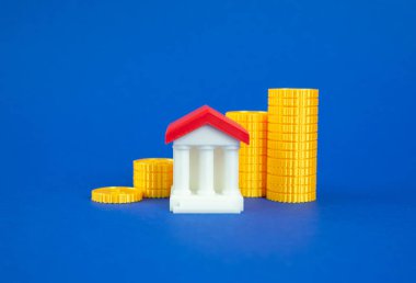 Artan bir düzende para yığını ve bir banka binası. Banka sermayesinin büyümesi. Banka hesabındaki tasarruf artışı. Artan banka sermayesi, mevduat artışı, artan tüketici tasarrufu.