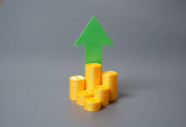 Yığınla bozuk para ve yukarı bakan yeşil ok. Finansal büyüme, gelir artışı veya yatırım başarısı. Enflasyon eğilimleri, sermaye birikimi veya piyasa iyimserliği ile ilgili.