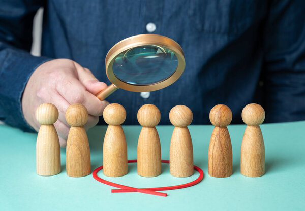 A man evaluates people figures through a magnifying glass. Search for candidates. Selection of people. HR management. Candidate review. Employment choice. Workforce selection.