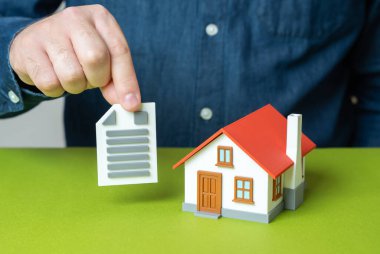 Evinin yakınında tapu senedi olan bir adam. Konut kira sözleşmesi. Emlak hakları, mortgage sözleşmesi, mülkiyet, yasal konut belgeleri