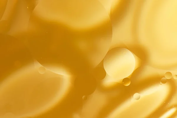 Yellow oil bubbles on water, cooking oil background.