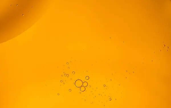 Yellow oil bubbles on water, cooking oil background.