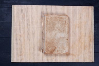 An old shabby light brown book on a bamboo stand, close-up top view