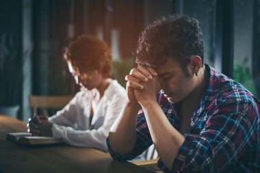 Asian Christian groups sitting within the Church Catholic. They clasped hands and closed his eyes and prayed for blessings from God. A pale sun shone in a place of worship with copy space. clipart