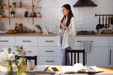 Gözlüklü kadın sanal derste ve evde online eğitim görürken bilgisayarında video görüşmesi yapıyor.