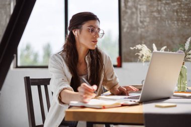 Evdeki masadaki dizüstü bilgisayarların yanında kablosuz kulaklık kullanan serbest çalışan biri.