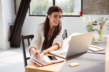 Kulaklıkta başarılı bir serbest yazar. Evdeki dizüstü bilgisayara ve akıllı telefona bakıyor. 