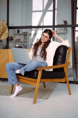 Memleketteki koltukta dizüstü bilgisayar kullanan neşeli kadın serbest yazar.